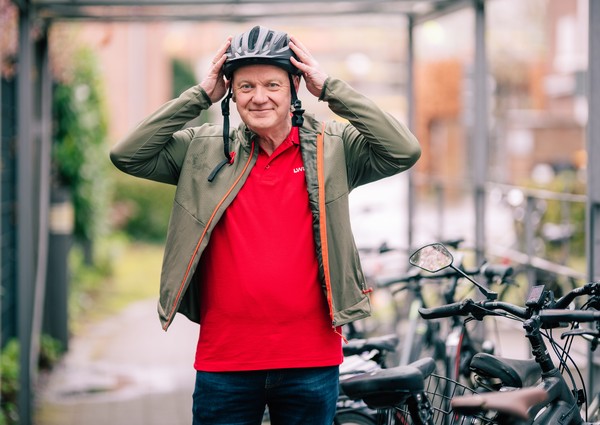 Hermann-Josef Emmericht steht neben seinem Fahrrad und zieht sich gerade den Helm an.