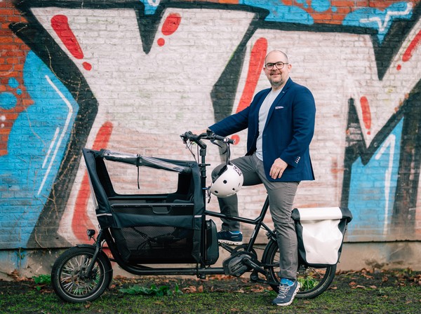 Thomas Auf der Landwehr steht mit seinem Lastenrad vor einer Wand mit Graffiti.