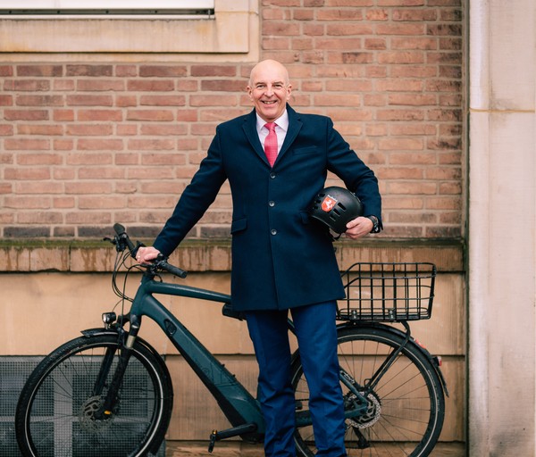 Herr Dr. Lunemann steht mit seinem Fahrrad und einem Helm unterm Arm vorm LWL-Landesgebäude.