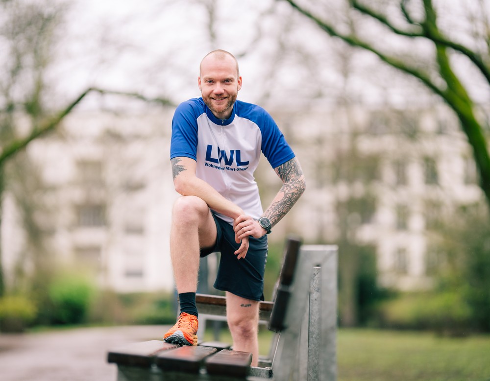 Nils Wehrenbrecht steht mit einem Bein auf einer Bank und lehnt sich leicht nach vorne.