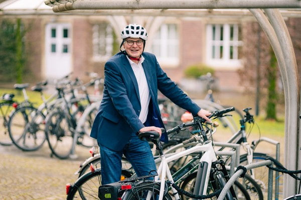 Dieter Skirde schiebt sein Fahrrad an eine Abstellanlage. Er hat einen Helm auf.